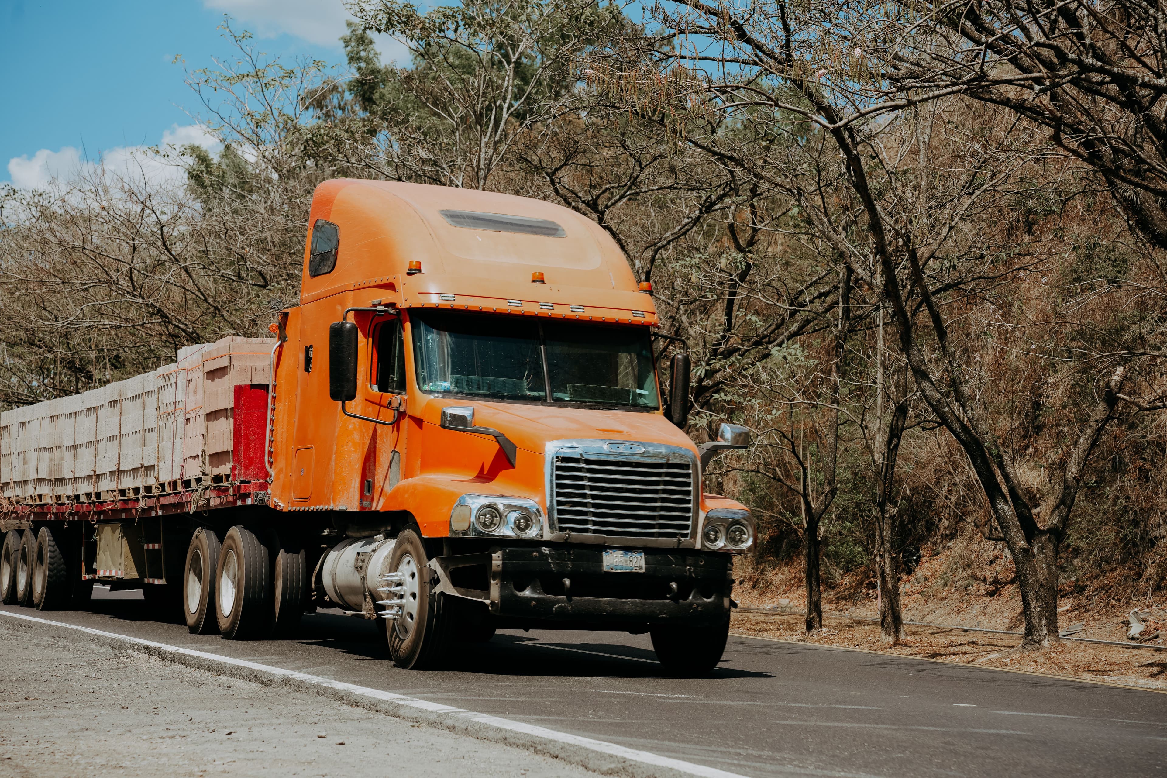 Freightliner conventional cab hauling a flatbed trailer